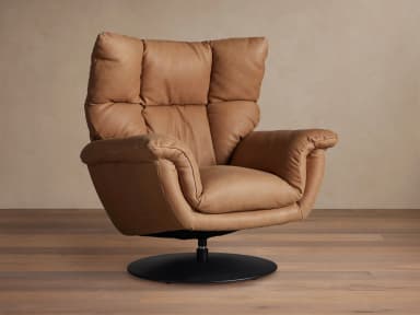 A contemporary armchair upholstered in tan leather, featuring a plush, segmented backrest and seat, rounded armrests, and a circular swivel base in black metal. The design emphasizes comfort with its soft, yielding upholstery and supportive structure. — 3D model