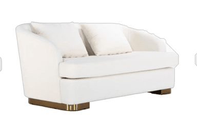 A contemporary loveseat featuring plush white or cream fabric upholstery and a distinctive brass-toned plinth base. The design incorporates gently curved arms and backrest, offering a soft, inviting aesthetic. It is equipped with two seat cushions and two matching back pillows, providing comfortable seating for two individuals. The overall form factor is compact and refined. — 3D model