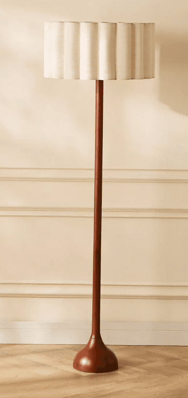 A tall, slender floor lamp featuring a dark wooden base and stem, complemented by an off-white, pleated fabric shade with a distinctive scalloped top rim. — 3D model