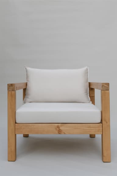 A single armchair with a solid wood frame and upholstered cushions. The frame consists of thick, square-profile wooden beams for the legs, base, and arms. The seat and back are padded with white cushions. A rectangular lumbar pillow is placed against the back cushion. — 3D model