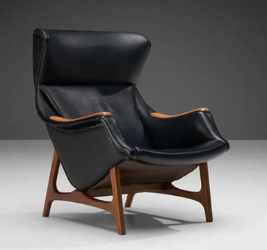 A high-backed armchair with a distinctive, sculptural form. The seat and backrest are upholstered in black material, possibly leather, and accented with numerous small decorative studs along the edges. The arms appear to be crafted from a lighter-colored wood, contrasting with the main upholstery. The chair is supported by a sculpted wooden base with a dark wood finish, featuring angled legs that provide stability. — 3D model