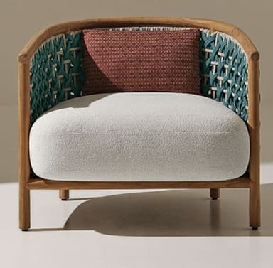 A contemporary lounge chair featuring a rounded wooden frame and an intricate geometric woven back and sides. The chair includes a thick, light-colored upholstered seat cushion and is accessorized with a smaller, textured terracotta-colored throw pillow. The design combines natural wood tones with a deep green woven pattern. — 3D model