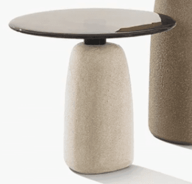 A contemporary side table featuring a sculptural, rounded concrete base and a thin, circular dark metal top. The base has a textured, porous finish, while the top is smooth and matte. The design is minimalist and uses contrasting materials for visual interest. — 3D model