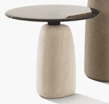 A contemporary side table featuring a sculptural, rounded concrete base and a thin, circular dark metal top. The base has a textured, porous finish, while the top is smooth and matte. The design is minimalist and uses contrasting materials for visual interest. — 3D model