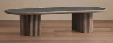 An elegant contemporary coffee table featuring an elongated oval dark green marble top with subtle white veining. The tabletop rests on two robust cylindrical pedestal bases, each finished with a distinct reeded or fluted texture in a warm brown wood tone. The overall design suggests a modern, sophisticated aesthetic. — 3D model