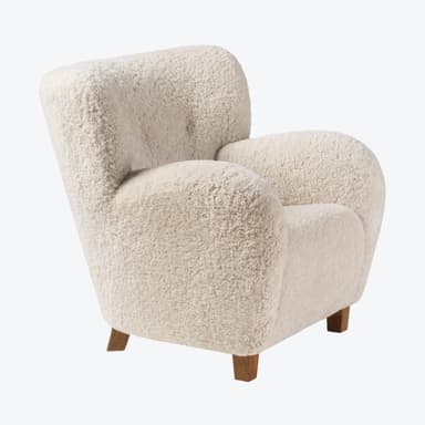An inviting upholstered armchair featuring a plush cream-colored sheepskin or bouclé fabric, with a rounded silhouette, integrated armrests, and subtle wooden legs. — 3D model