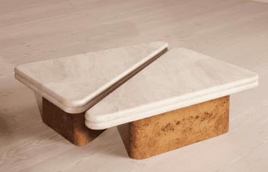 A modular coffee table set consisting of two triangular units. Each unit features a thick, rounded tabletop made of light beige travertine, resting on a geometric base constructed from golden-brown burl wood. — 3D model