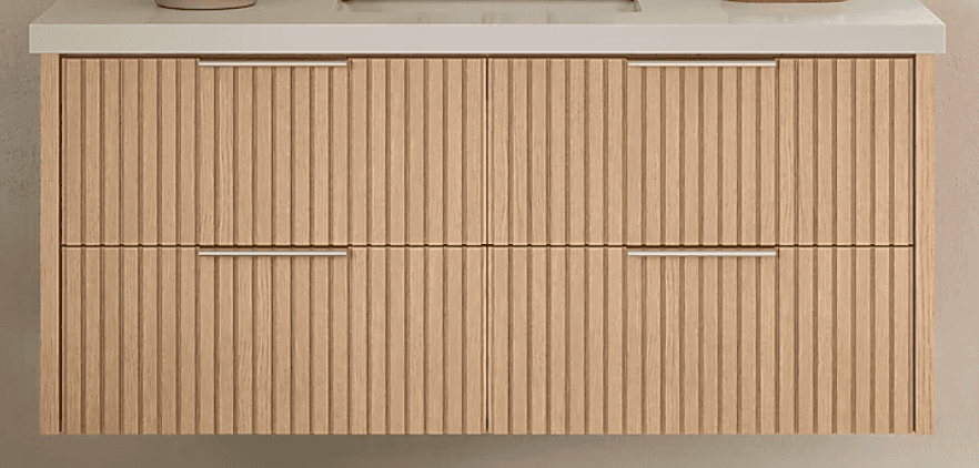 A modern bathroom vanity featuring a light wood-toned base with a distinctive fluted or reeded texture on its two drawer fronts. It is topped with a smooth, light-colored solid surface countertop and includes two minimalist silver-tone bar handles. — 3D model