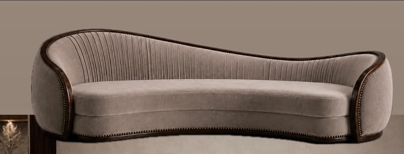 A gracefully curved sofa upholstered in a light beige velvet, featuring a prominent dark wood trim with decorative nailhead detailing along its serpentine backrest and base. The interior backrest exhibits vertical channel tufting. — 3D model