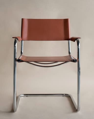 A modern armchair with a tubular chrome frame and leather upholstery. The seat and backrest are made of brown leather straps, and the armrests are also upholstered in leather. The frame is constructed from bent tubular metal, forming legs that extend upwards to support the seat and back. — 3D model