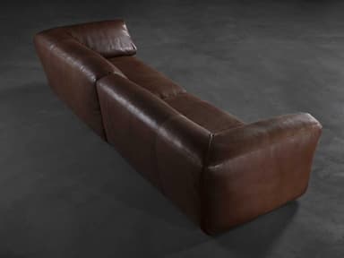 A contemporary brown leather sofa, characterized by its low-profile design and generously padded, inward-sloping arms. The seating features two large, plush cushions, suggesting a comfortable and relaxed seating experience. The leather exhibits a slightly worn, supple texture, hinting at quality material. — 3D model