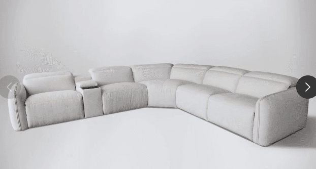 A large, L-shaped reclining sectional sofa upholstered in light beige, textured fabric. It features multiple modular components, including two end recliners with adjustable headrests and an integrated console with two cup holders between two seats. The design is contemporary with clean lines. — 3D model
