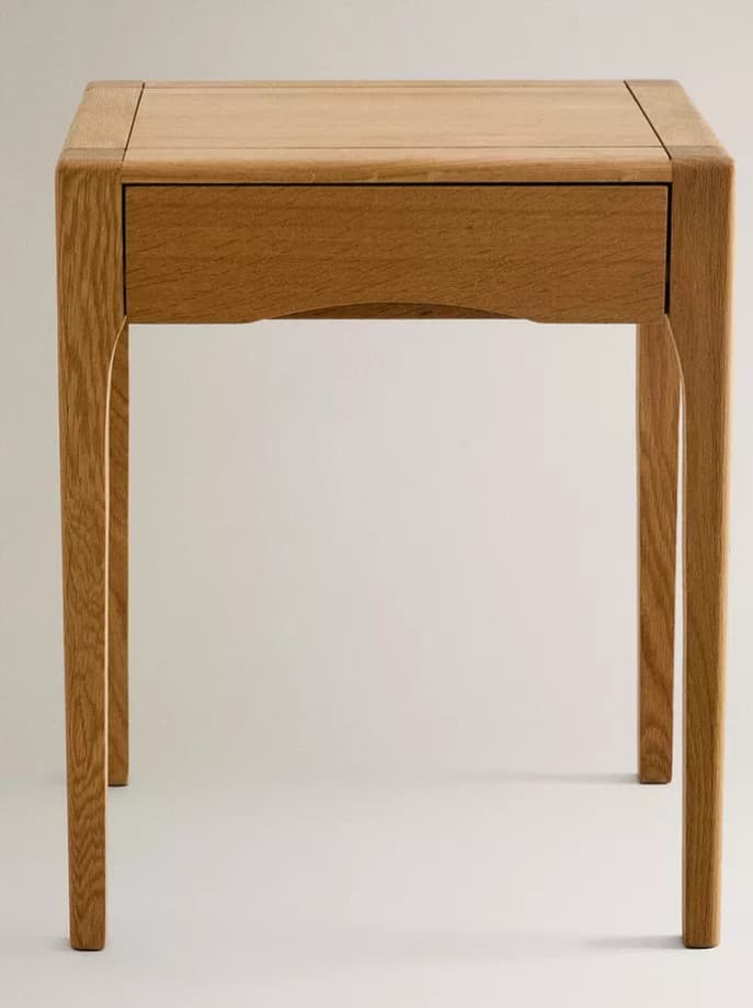 A light-toned wooden nightstand or side table, characterized by its clean, minimalist design and sturdy construction. It features a single, recessed drawer with a subtle, integrated curved handle and four slender, straight legs. The wood exhibits a fine grain, indicative of oak or a similar hardwood. — 3D model
