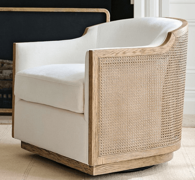 A contemporary swivel accent chair featuring an exposed light-toned wood frame with natural cane webbing panels on the exterior. The interior seat and curved backrest are upholstered in a light, off-white fabric, and it rests on a concealed swivel base. — 3D model
