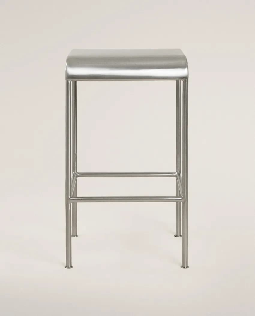 A minimalist, contemporary bar stool constructed from brushed metal, featuring a rectangular seat with subtly rounded edges and a four-legged base with an integrated footrest. — 3D model