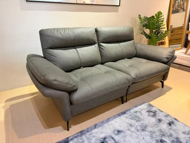 A modern two-seater sofa with plush, channeled backrests and seat cushions. The sofa features slightly rounded armrests and is supported by slender black metal legs. The upholstery appears to be a textured fabric in a neutral gray tone. — 3D model