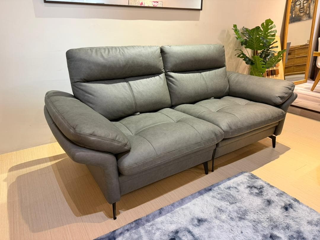 A modern two-seater sofa with plush, channeled backrests and seat cushions. The sofa features slightly rounded armrests and is supported by slender black metal legs. The upholstery appears to be a textured fabric in a neutral gray tone. — 3D model
