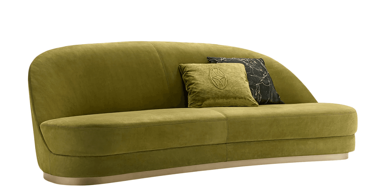A modern, curved sofa upholstered in a soft, olive-green velvet-like fabric. The sofa features a rounded backrest that extends to armrests, and a distinctively shaped seat with subtle horizontal stitching. It is supported by a thin, brushed metallic base that follows the gentle curve of the sofa. Two decorative throw pillows are placed on the seat; one is a matching olive-green with a textured, embossed circular pattern, and the other is dark with a marbled pattern. — 3D model