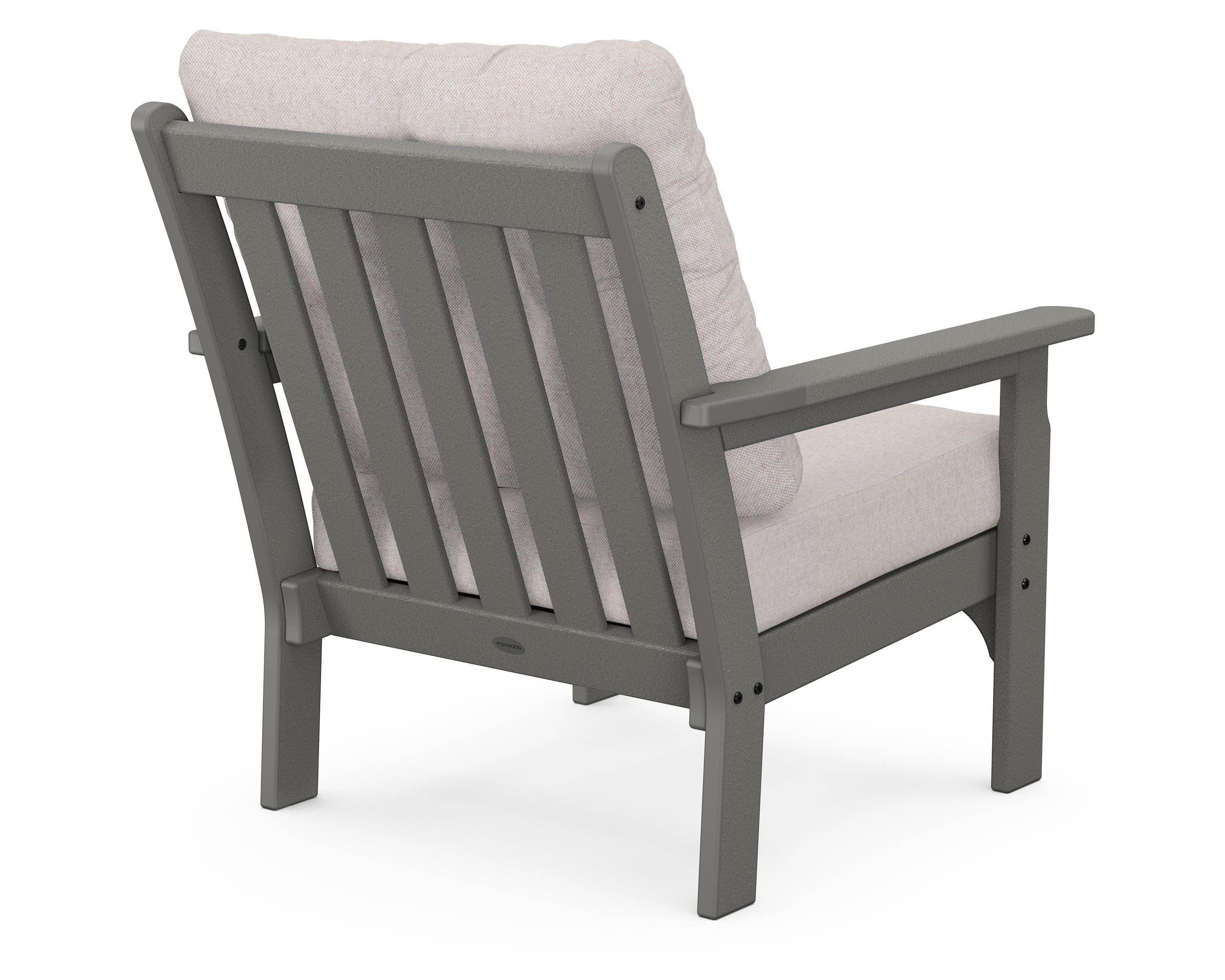 A gray outdoor armchair with a slatted backrest and upholstered seat and back cushions. The armchair features wide armrests and is constructed from a durable, weather-resistant material. It is designed for comfort and durability in an outdoor setting. — 3D model