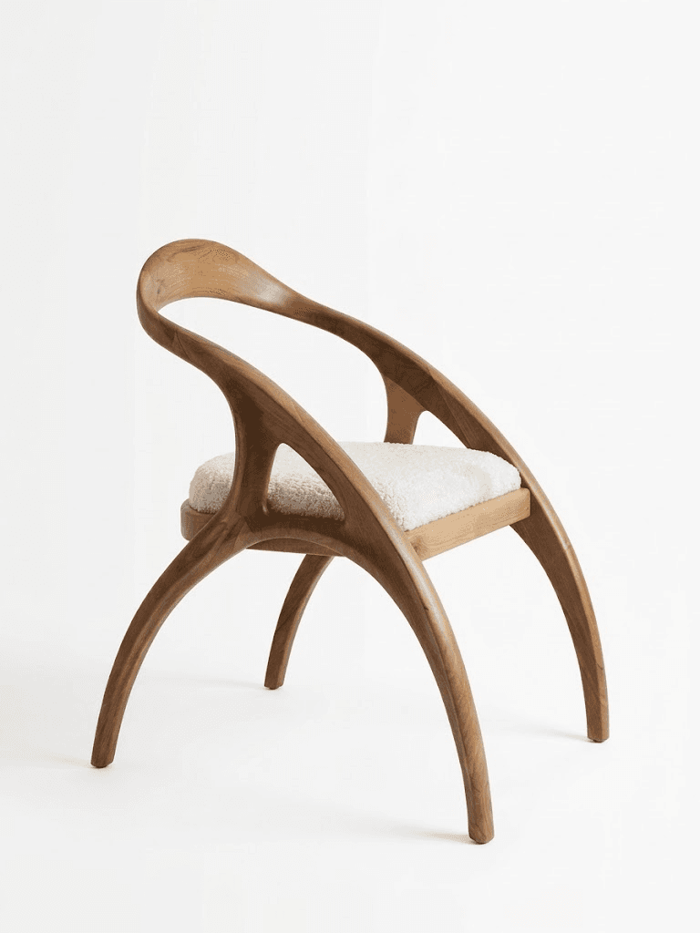 A sculptural armchair featuring a curved solid wood frame and a plush, light-colored upholstered seat. The design emphasizes organic forms with flowing lines and distinctive splayed legs. — 3D model