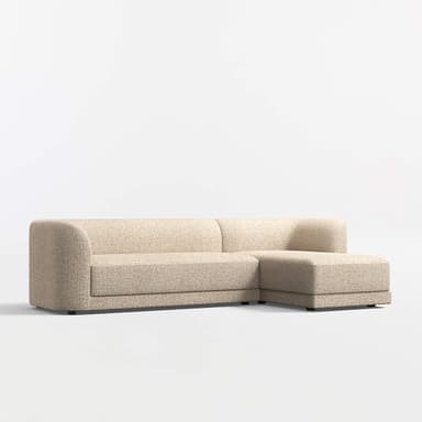 A sectional sofa with a chaise lounge attachment. The sofa features rounded armrests and a low profile design. It is upholstered in a textured fabric with a speckled pattern. The base is a dark, flat plinth or low legs. — 3D model