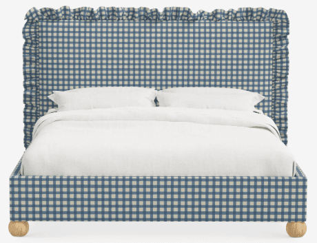 A bed featuring an upholstered headboard and frame in a blue and white gingham fabric. The headboard is designed with a distinctive ruffled trim along its top and side edges. The bed frame is supported by four spherical light-toned wooden feet. White bedding, including pillows and a duvet, is present on the bed. — 3D model