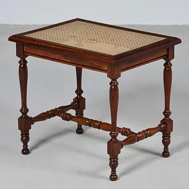 A rectangular accent table constructed from dark brown turned wood with a woven cane top. It features decorative turned legs connected by X-shaped stretcher bars near the base, terminating in ball feet. — 3D model