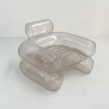 An inflatable armchair with a distinct translucent, smoky brown hue. The design features large, cylindrical forms for the armrests, base, and backrest, creating a plush and rounded silhouette. Seams are visible where the inflatable sections are joined, indicating its construction method. The material appears to be a flexible plastic or vinyl. — 3D model