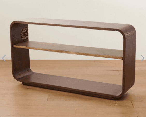 A minimalist console table featuring a curved, continuous frame that forms the legs and tabletop. It has a single, horizontal shelf suspended between the curved supports. The design emphasizes smooth, flowing lines and a lack of sharp edges. The overall structure is robust and appears to be made from wood or a wood composite. — 3D model