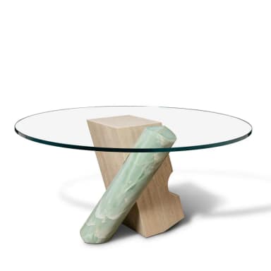 A contemporary coffee table featuring a circular glass top supported by an abstract sculptural base. The base is composed of two distinct elements: one is a light-colored, textured block with carved indentations, appearing to be travertine; the other is a cylindrical element with a veined, translucent green stone, likely onyx, integrated with the first block. The overall design is avant-garde and sculptural. — 3D model