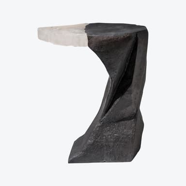 A sculptural accent table featuring an abstract, angular base crafted from a dark, rough-textured material. The tabletop is distinctly divided, with one half continuing the dark, coarse texture of the base, and the other half composed of a contrasting light, translucent, and striated material, possibly crystal or alabaster, creating a stark visual contrast. — 3D model