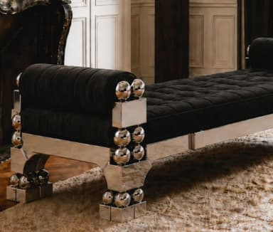 A striking postmodern daybed featuring a polished chrome frame with intricate geometric and spherical details, paired with a tufted, rich brown upholstered cushion and cylindrical bolster pillows at each end. The metallic frame consists of rectangular and triangular elements adorned with stacked chrome spheres, creating a bold and reflective aesthetic. — 3D model