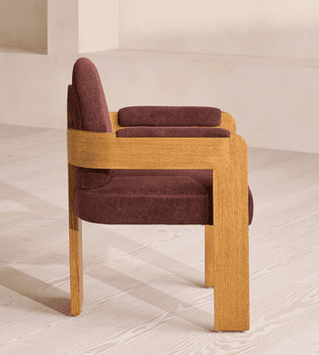 A modern armchair featuring a sturdy wooden frame and rich burgundy upholstery. The design incorporates solid, block-like wooden armrests and legs, with a gently curved, upholstered backrest and seat. The armrests also have padded cushions for added comfort. — 3D model