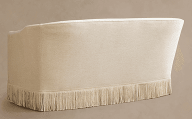 A contemporary loveseat upholstered in a light cream fabric, featuring a curved back, gently rolled armrests, a single seat cushion, and a distinctive decorative fringe skirt along the entire base. — 3D model