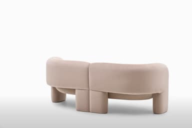 A contemporary loveseat upholstered in a light, neutral fabric, featuring a distinctive curved backrest and integrated rounded armrests. The piece has a monolithic appearance with no visible legs, suggesting a continuous, low-profile base. The design emphasizes soft lines and a plush, inviting form, suitable for modern interior settings. The fabric appears to have a subtle texture. — 3D model