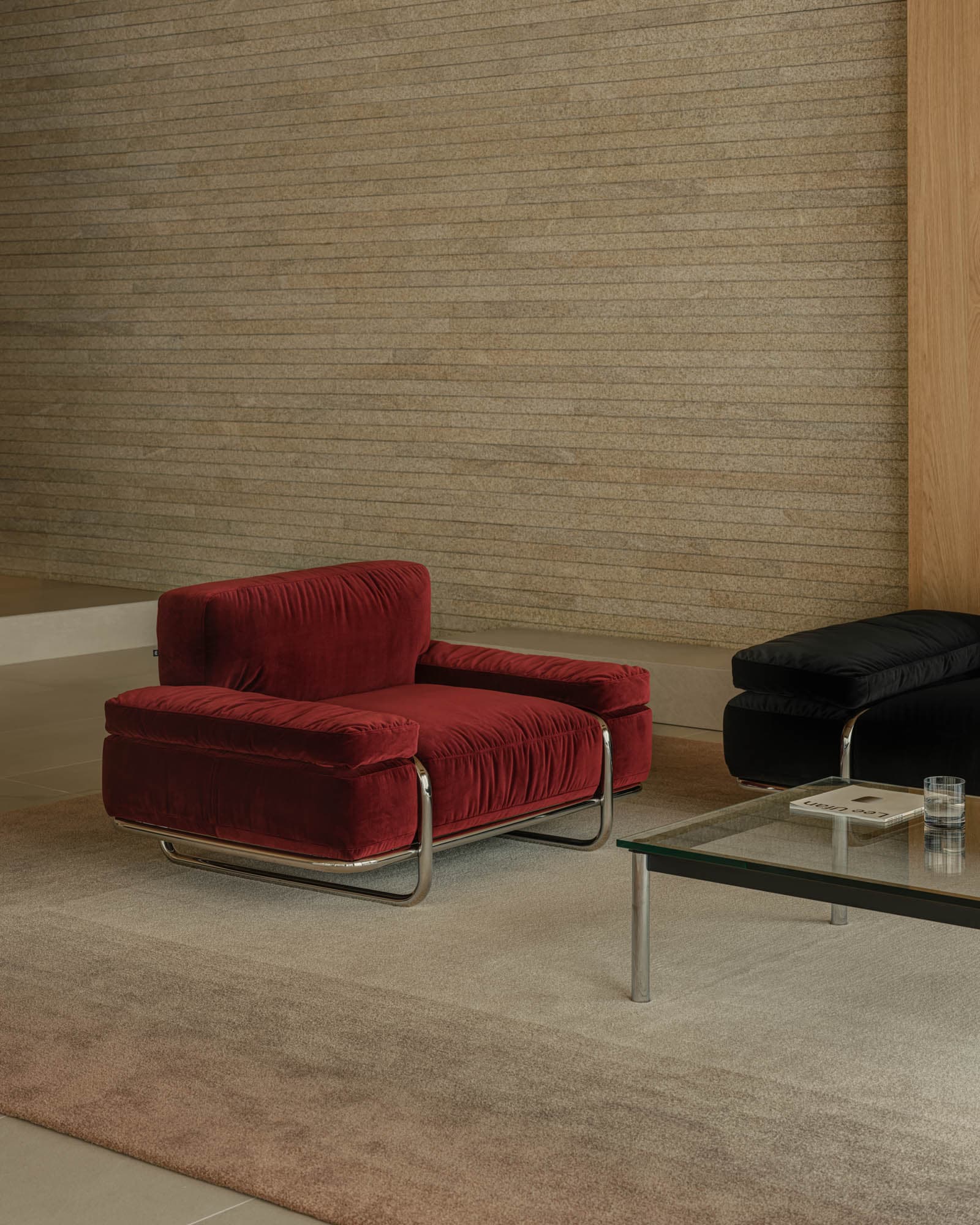 A single-seat armchair with a plush, deep red velvet upholstery. The armchair features a low-profile design with generously padded seat, back, and armrests. It is supported by a sleek, modern chrome metal frame that forms a cantilever base with rounded edges. The upholstery has a subtle tufted texture. — 3D model