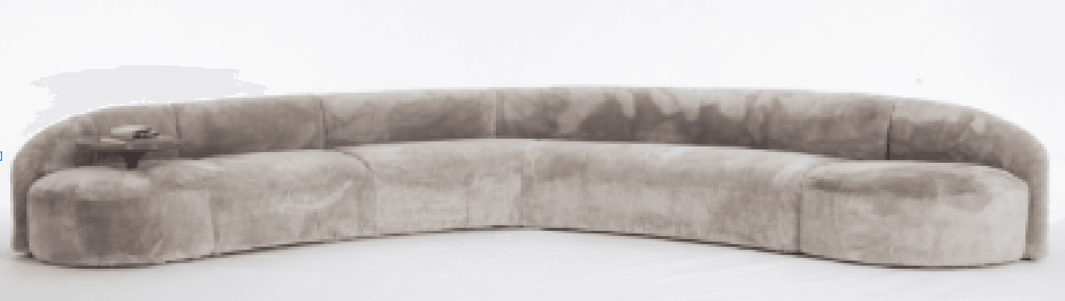 A long, curved sofa with a plush, textured upholstery. The sofa features a continuous, rounded backrest and seat. On the left side of the sofa, a small, integrated side table or armrest extension with a wooden top is visible. The overall form is modern and organic. — 3D model