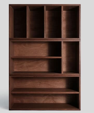 A vertical, modular shelving unit constructed from dark brown wood, featuring multiple open compartments of varying sizes. The unit is composed of three stacked sections, each offering different configurations of shelves and cubbies. The top section has several narrow vertical compartments, the middle section has a wider shelf and smaller vertical divisions, and the bottom section contains two broad horizontal shelves. The wood grain is visible through the dark stain, giving it a natural yet refined appearance. — 3D model