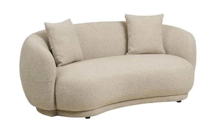 A modern, bouclé upholstered sofa with a curved silhouette. It features rounded armrests that blend seamlessly into the backrest, and a gently arcing seat base. Two rectangular throw pillows with matching upholstery are placed on the sofa. The sofa is supported by low-profile, dark-colored feet. — 3D model