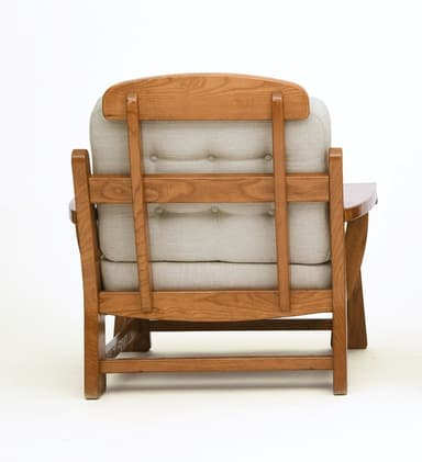 A sturdy, craftsman-style lounge chair featuring a solid oak wood frame and thick, upholstered cushions. The chair has broad, rounded arms, slatted side panels, and block legs. The back cushion is button-tufted. — 3D model