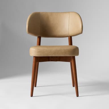 A tan upholstered accent chair with a curved backrest and a cushioned seat. The chair features a wooden frame with four tapered legs. The upholstery appears to be leather or a leather-like material, with visible stitching details on the backrest and seat cushion. The wooden legs and frame have a medium-toned finish. — 3D model
