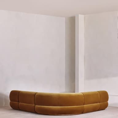 A modular sectional sofa with rounded edges and a plush velvet upholstery. The sofa is configured in a corner arrangement, featuring deep seats and back cushions with horizontal tufting. The design is low-profile and appears to be upholstered in a warm, mustard-yellow or ochre velvet fabric. — 3D model