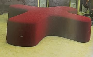 A vibrant red upholstered modular seating unit, characterized by its distinctive X-shaped or four-lobed design. The entire piece is covered in a textured red fabric, and all edges are softly rounded, creating a smooth and inviting aesthetic. It appears to be a contemporary design suitable for flexible lounge arrangements. — 3D model