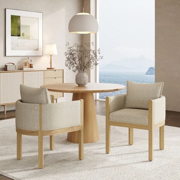 A contemporary armchair featuring an exposed light-colored wooden frame with a beige fabric upholstery. The chair includes a padded seat, back, and armrests, complemented by a loose back cushion for added comfort. The design emphasizes clean lines and a minimalist aesthetic. — 3D model
