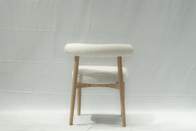 A contemporary side chair with a rounded backrest and seat upholstered in a textured, boucle fabric. The chair features a light-colored wooden frame with four tapered legs. The design is minimalist and modern. — 3D model