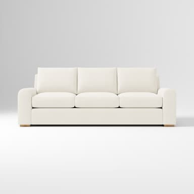 A contemporary three-seater sofa, viewed from the rear, featuring three loose back cushions and a low-profile base. The sofa is upholstered in a light-colored, possibly off-white or cream, textured fabric. The arms appear gently rounded on the outer edges. Small, recessed wooden feet are visible at the base corners. — 3D model