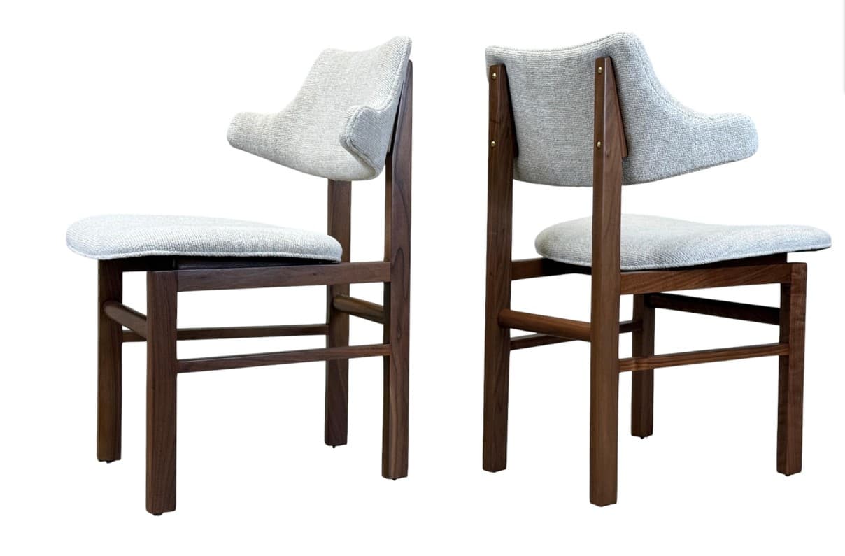 A contemporary dining chair featuring a dark wood frame and light gray fabric upholstery. The chair has a distinctive sculpted backrest with a slight curve, providing an ergonomic and stylish profile. The four-legged frame is constructed from solid wood, suggesting durability and stability. — 3D model