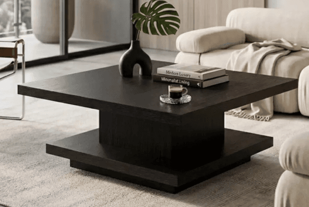 A minimalist square coffee table featuring a two-tiered design in a dark wood finish. The table consists of a flat, square top surface elevated above a matching square base by a shorter, central square block, creating a floating appearance. The material appears to be engineered wood with a dark wood grain laminate or veneer, exhibiting clean lines and a contemporary aesthetic. — 3D model