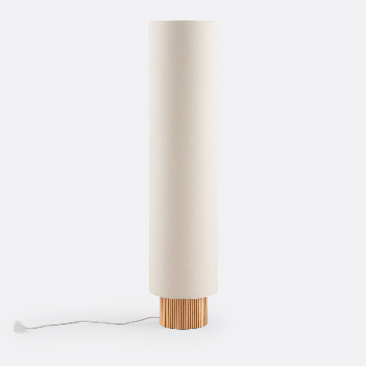 A contemporary floor lamp featuring a tall, slender cylindrical shade made of off-white fabric, resting upon a round base constructed from light-toned wood with a distinctive fluted or reeded texture. A power cord extends from the base. — 3D model