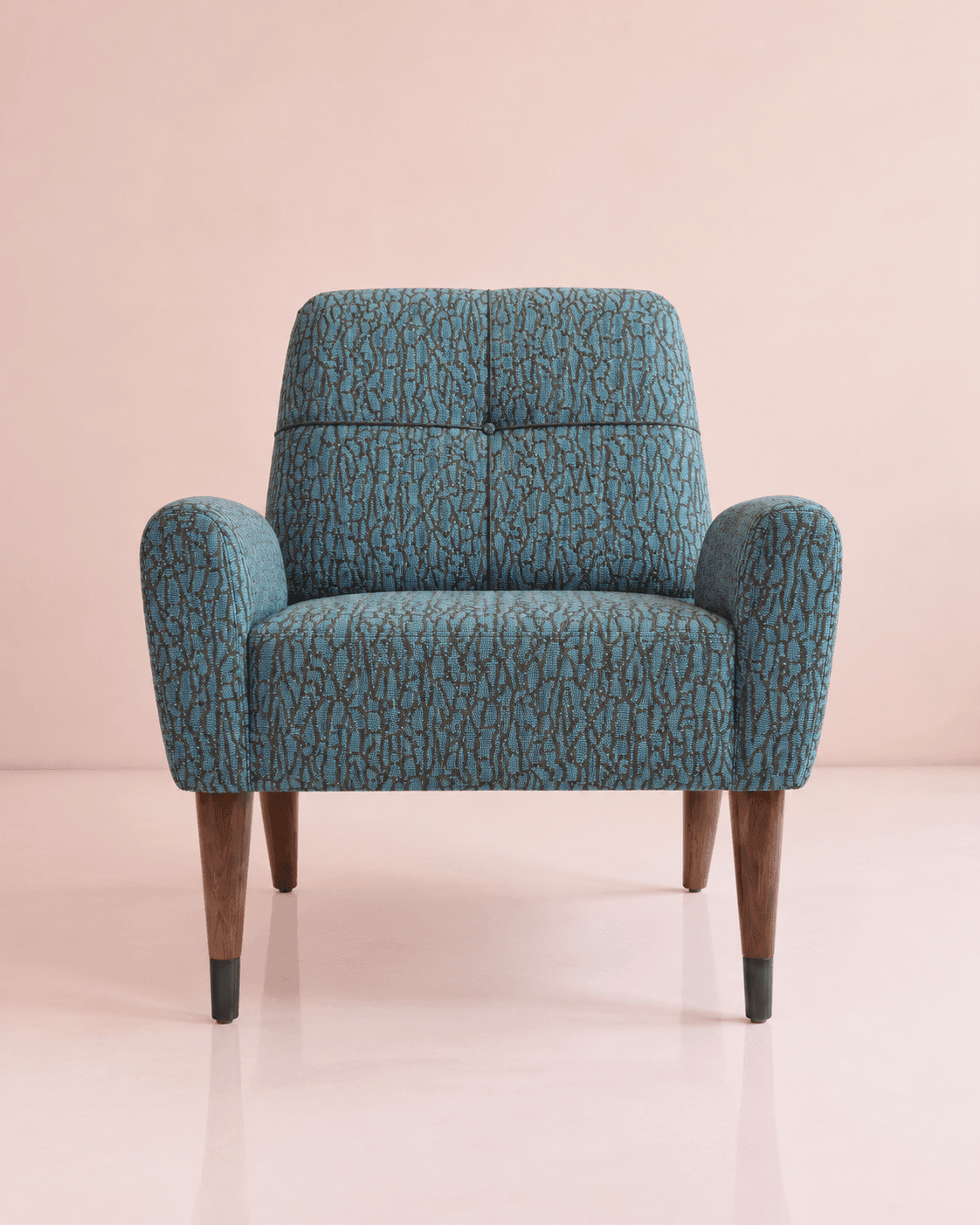 A retro-inspired armchair featuring a distinctive patterned teal fabric upholstery and tapered wooden legs with metal caps. The backrest shows subtle button tufting, and the armrests are gently curved. The overall form suggests a comfortable, supportive seat. — 3D model